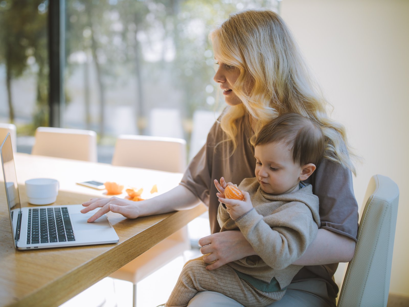 woman-carrying-her-baby-and-working-on-a-laptop-4079281
